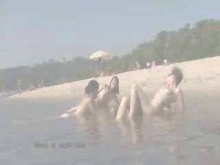 Um público praia heats para cima com dois superior boneca nudists